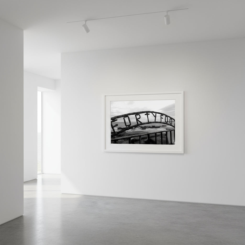 Monochrome seascape photo capturing the serene beauty of the Forty Foot bathing spot in Dublin, Ireland. Martello tower stands in the distance against a clear sky.